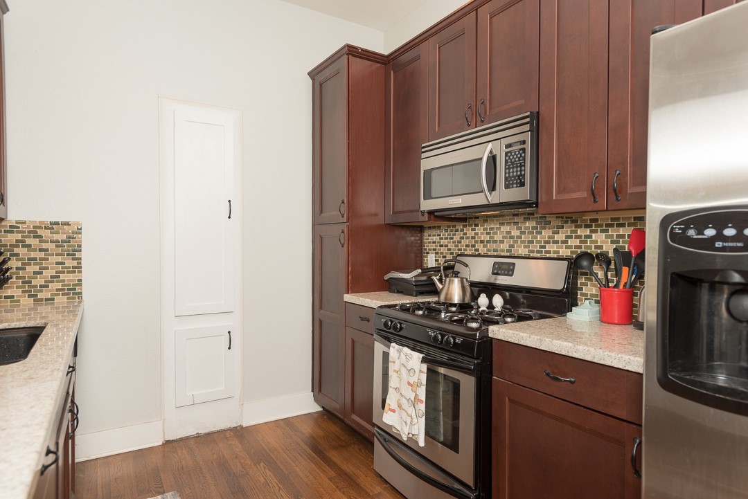 2805 Lafayette Avenue Austin, TX 78722 - Photo 10 of 23 Kitchen with appliances with stainless steel finishes, tasteful backsplash, dark wood-style floors, and baseboards