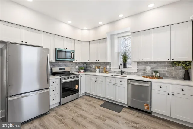a kitchen with white cabinets stainless steel appliances and a window