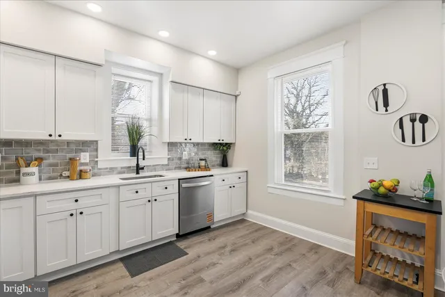 a kitchen with white cabinets and window
