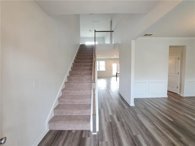 a view of an empty room with wooden floor and fan