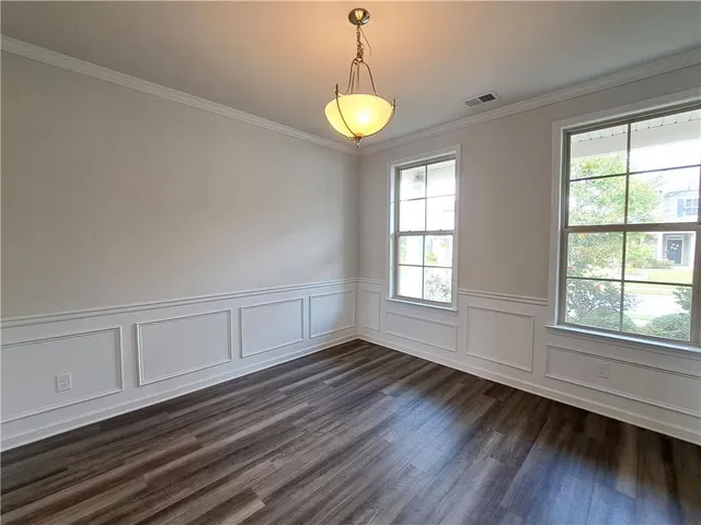 a view of an empty room with wooden floor and stairs