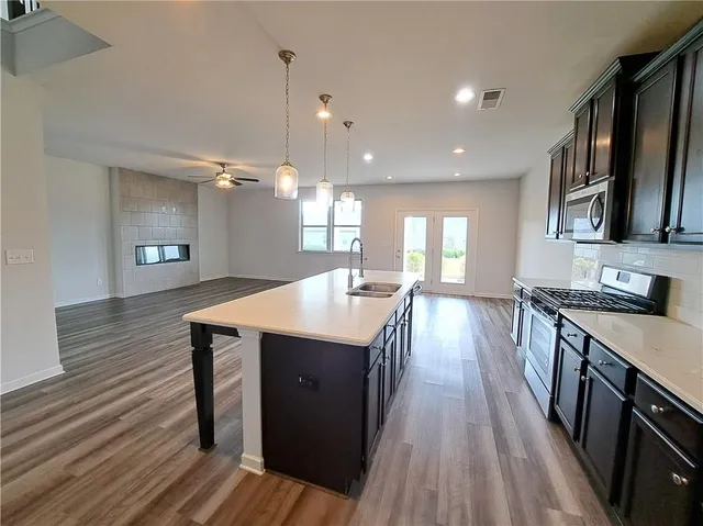 a kitchen with kitchen island granite countertop a stove a microwave a sink a refrigerator and wooden cabinets