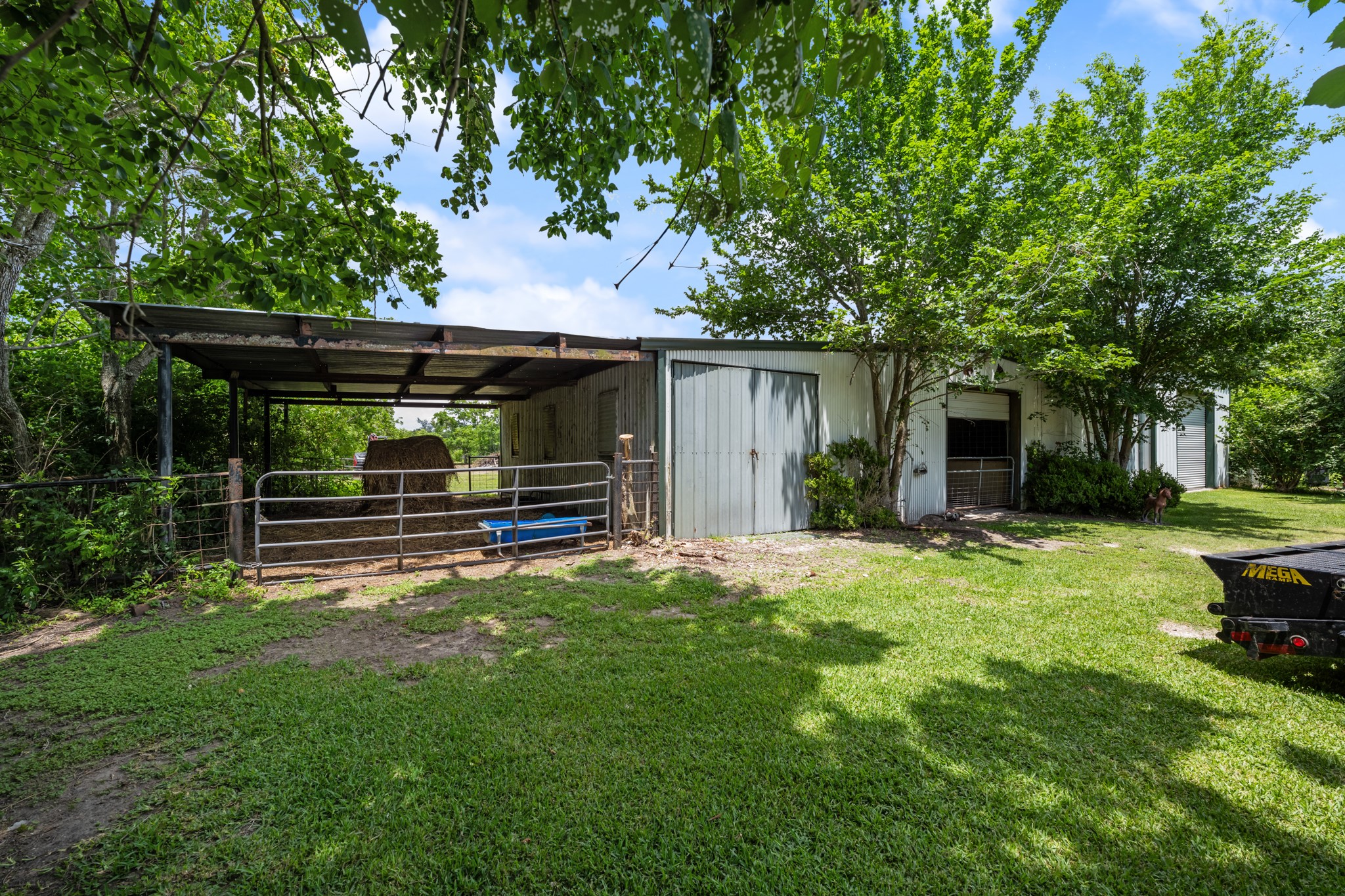 15602 Fir Road Santa Fe, TX 77517 - Photo 36 of 42 Functional horse barn with covered stalls and fenced areas, offering excellent space for livestock care, feed storage, and everyday operations. Surrounded by mature trees and open green space for a peaceful country setting.