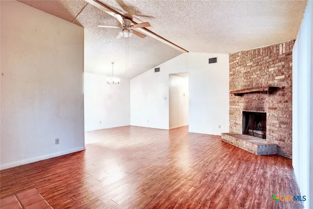 a view of a livingroom with wooden floor a fireplace and a window