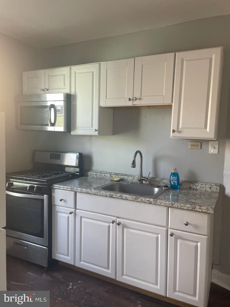 1111 South 4th Street, Unit B Camden, NJ 08103 - Photo 9 of 11 a kitchen with stainless steel appliances granite countertop white cabinets sink and granite counter tops