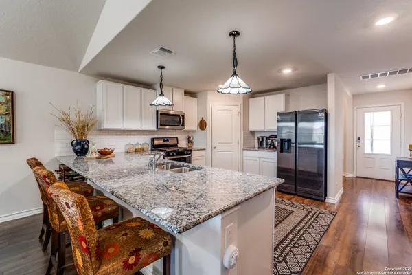 a kitchen with stainless steel appliances granite countertop a kitchen island a stove a table and chairs