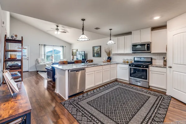 a kitchen with stainless steel appliances kitchen island granite countertop a stove top oven a sink a counter space and cabinets