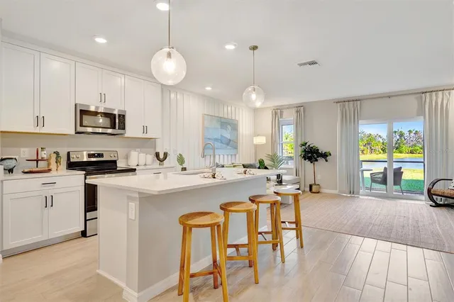 a kitchen with stainless steel appliances granite countertop a sink a stove a refrigerator cabinets and chairs