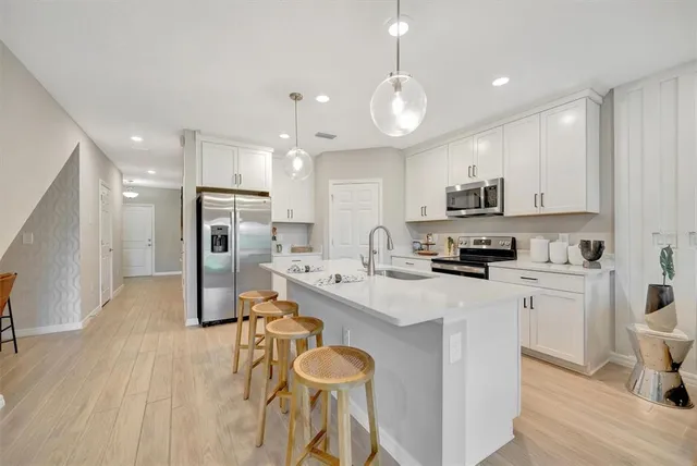 a large kitchen with stainless steel appliances a stove a sink dishwasher a microwave oven with a dining table and chairs