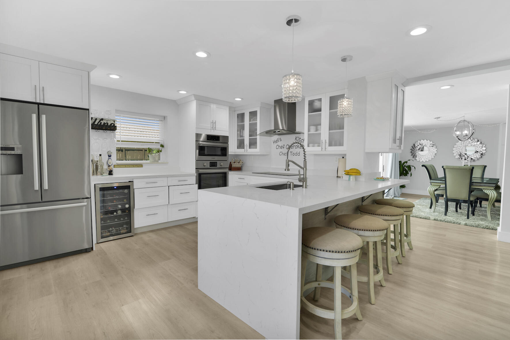 a kitchen with stainless steel appliances kitchen island granite countertop a dining table chairs and refrigerator