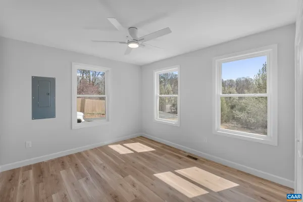 a view of empty room with wooden floor and fan