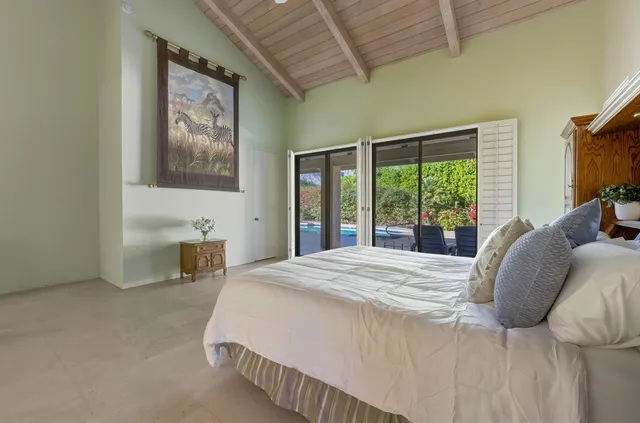 a bed sitting in a spacious bedroom next to a window