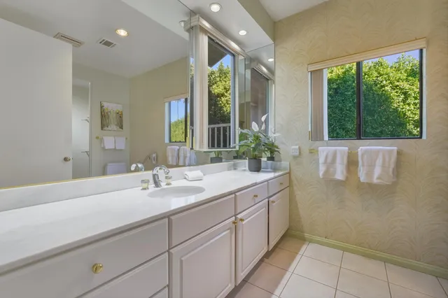 a bathroom with a double vanity sink a large mirror and a bathtub