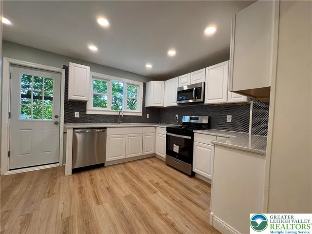 a kitchen with granite countertop a stove top oven a sink dishwasher and a refrigerator with wooden floor