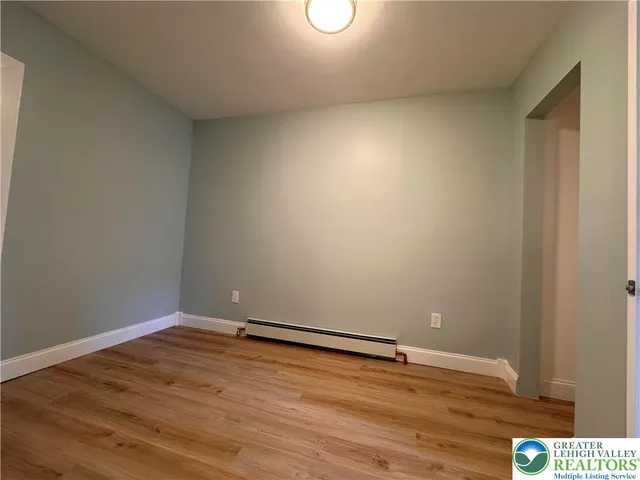 a view of an empty room with wooden floor and closet