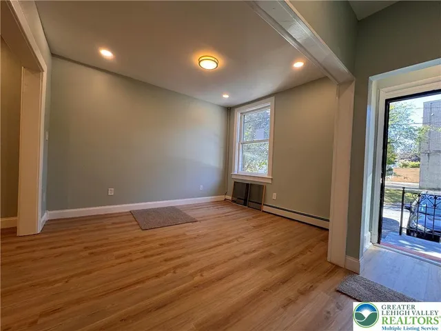a view of an empty room with wooden floor and a window
