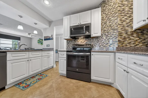 a kitchen with stainless steel appliances kitchen island granite countertop a refrigerator and a sink