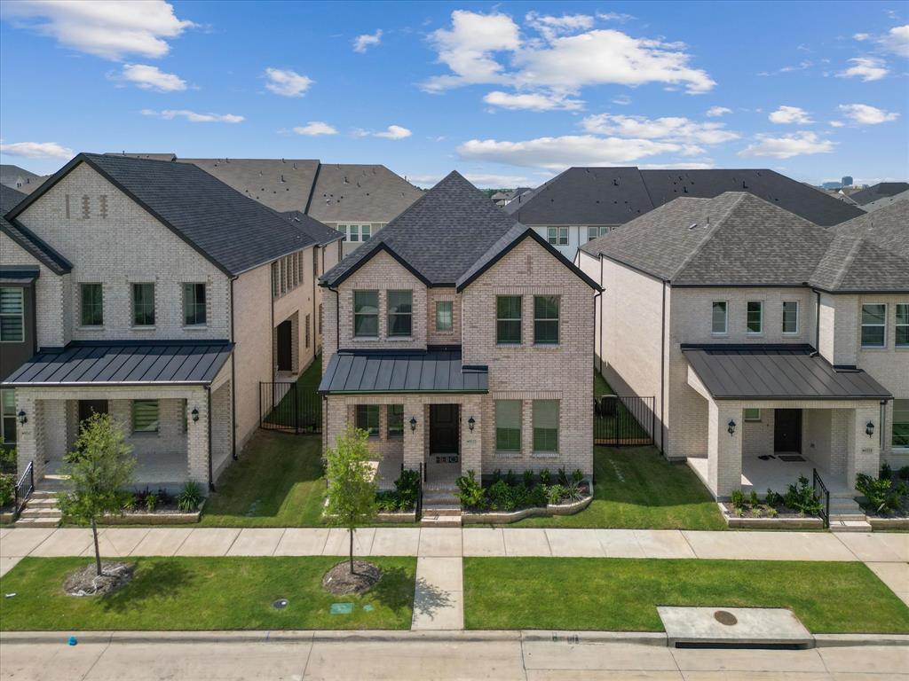 9533 Keep Street Frisco, TX 75035 - Photo 38 of 40 Two-story brick exterior featuring a black shingle roof, dark metal awnings, a covered front porch, and manicured front landscaping