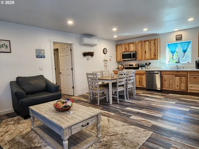 a living room with stainless steel appliances furniture and a kitchen view