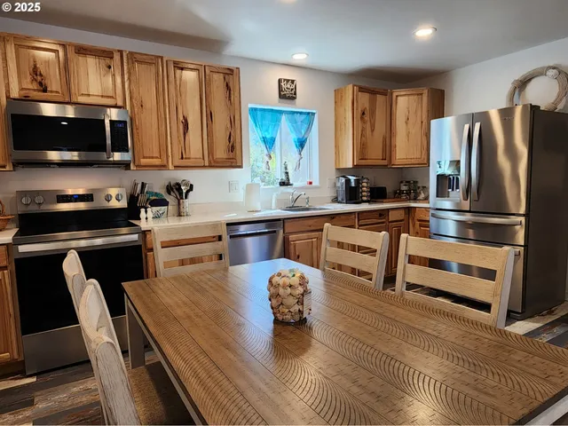 a kitchen with stainless steel appliances a stove a sink a microwave a refrigerator and cabinets