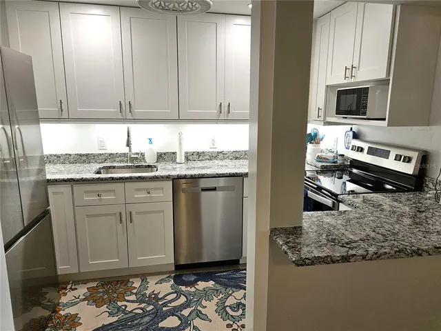 a kitchen with stainless steel appliances granite countertop a sink stove and cabinets