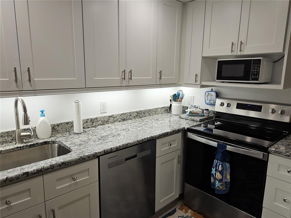 519 Albee Farm Road, Unit 114 Venice, FL 34285 - Photo 12 of 21 a kitchen with granite countertop white cabinets and black appliances