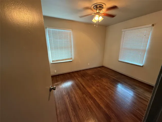 a view of empty room with wooden floor and fan
