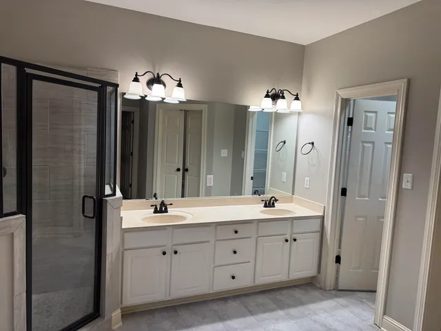 a spacious bathroom with a double vanity sink a large mirror a shower and a bathtub