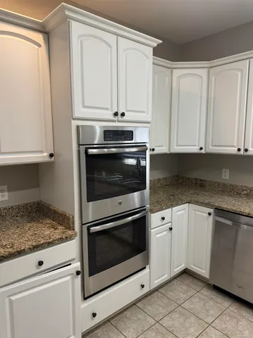 a kitchen with granite countertop white cabinets stainless steel appliances and a sink