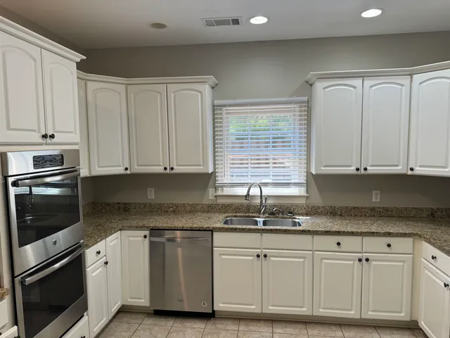 a kitchen with granite countertop white cabinets and stainless steel appliances