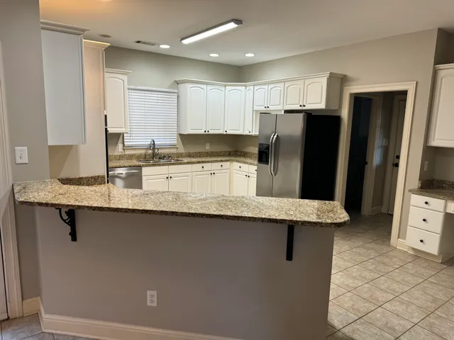 a kitchen with granite countertop a sink stainless steel appliances and white cabinets