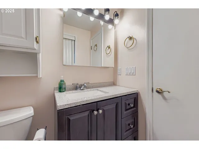 a bathroom with a granite countertop sink a toilet and mirror