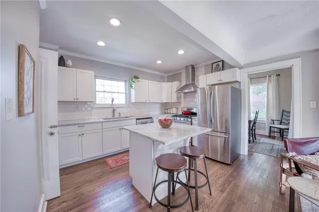 a kitchen with stainless steel appliances granite countertop a refrigerator a sink dishwasher a stove and white countertops with wooden floor