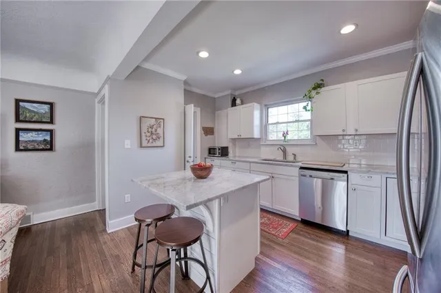 a kitchen with stainless steel appliances granite countertop a white cabinets and wooden floor