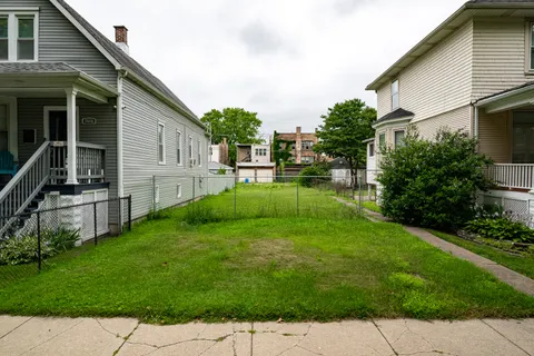 a backyard of a house with plants and wooden fence
