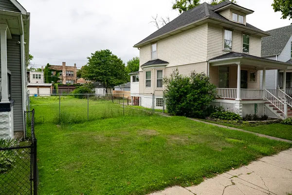 a white house that has a small yard and trees in the background