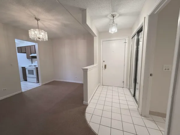 a view of a hallway with a chandelier fan and refrigerator