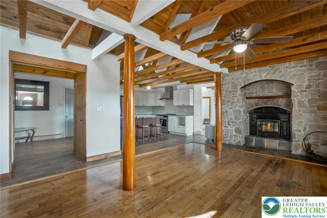 204 Ridge Cup Road New Ringgold, PA 17960 - Photo 7 of 72 Exposed beams complement a stone fireplace and gleaming wood floors in this inviting open-concept living area.