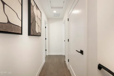 a view of a hallway with wooden floor and cabinet