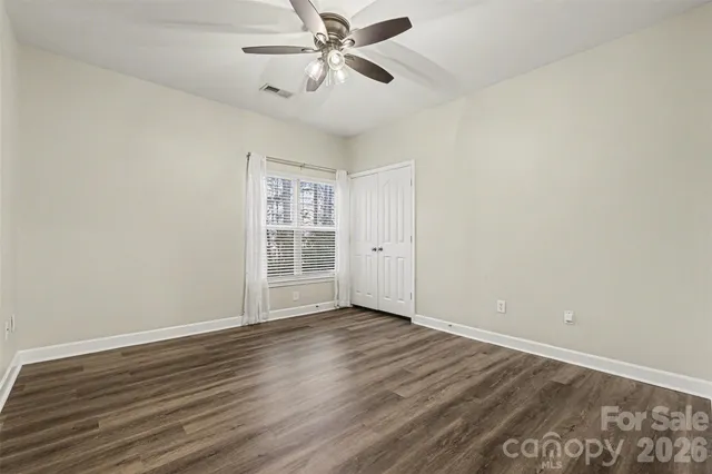 an empty room with wooden floor fan and windows