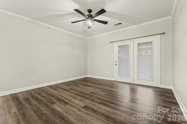 a view of an empty room with window and wooden floor