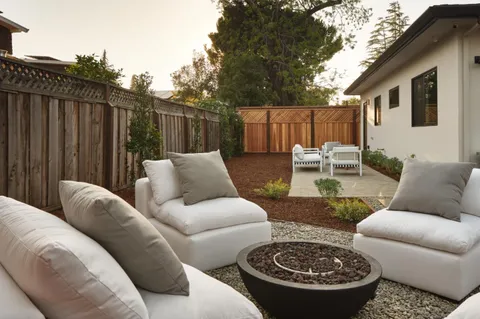 a view of a patio with couches table and chairs and wooden fence