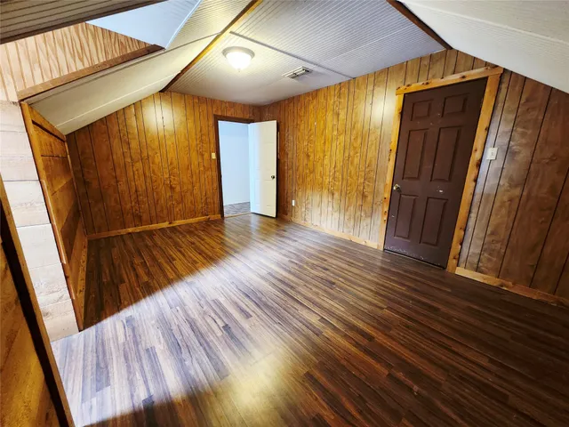 a view of an empty room with wooden floor and stairs