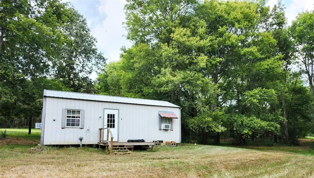 a small barn with a small yard and large trees