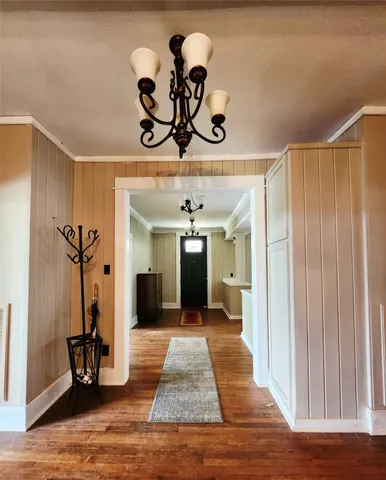 a view of a hallway with wooden floor and a chandelier