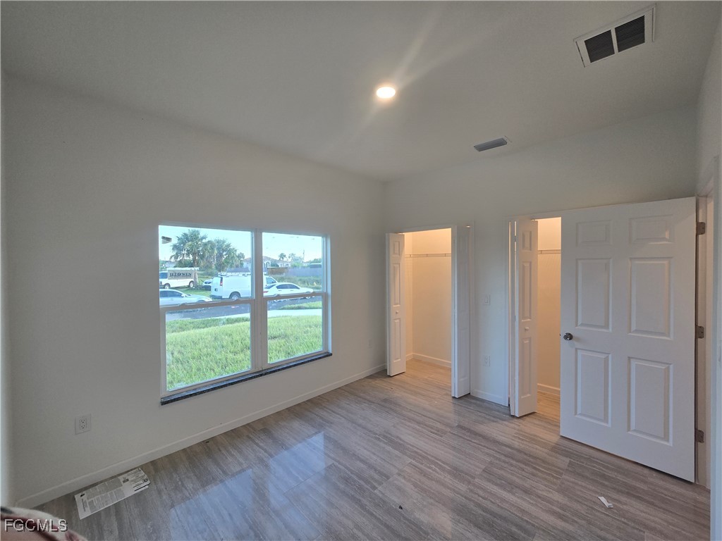 2822 19th Street Southwest Lehigh Acres, FL 33976 - Photo 11 of 23 an empty room with wooden floor and windows