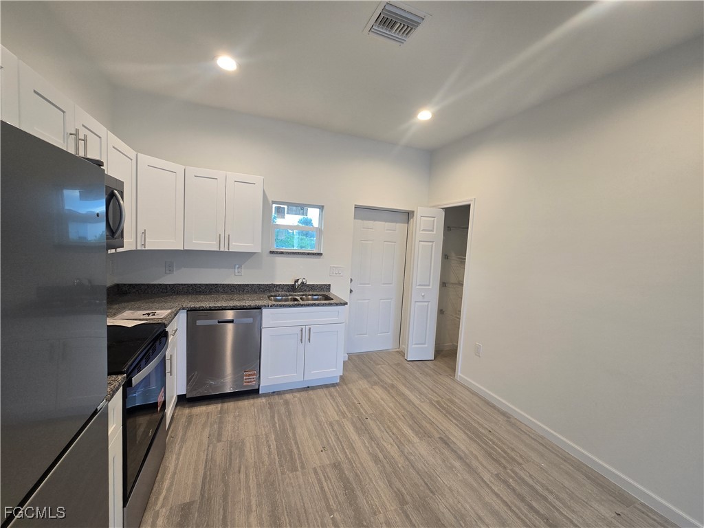 2822 19th Street Southwest Lehigh Acres, FL 33976 - Photo 9 of 23 a kitchen with a refrigerator and a stove top oven