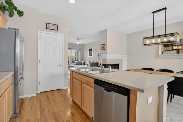 a kitchen with granite countertop a table chairs a sink dishwasher refrigerator and cabinets