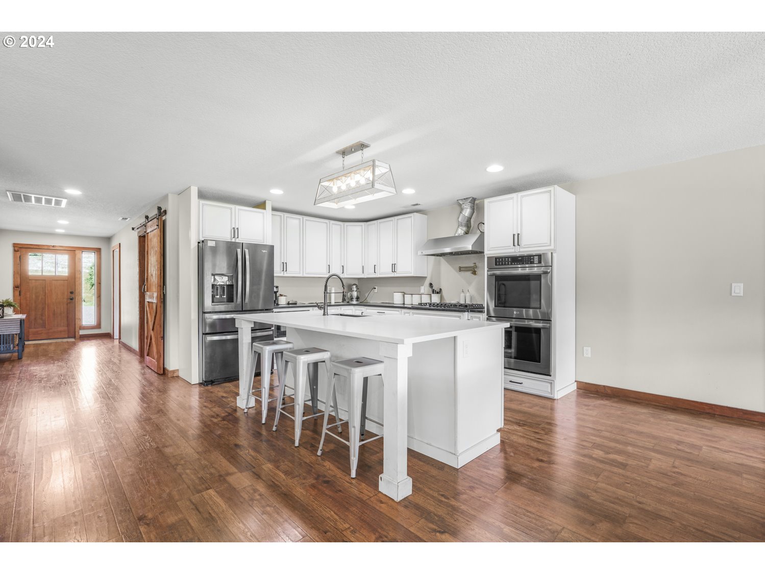 70200 Apiary Road Rainier, OR 97048 - Photo 12 of 37 a kitchen with stainless steel appliances kitchen island granite countertop a refrigerator a stove a sink and a dining table with wooden floor