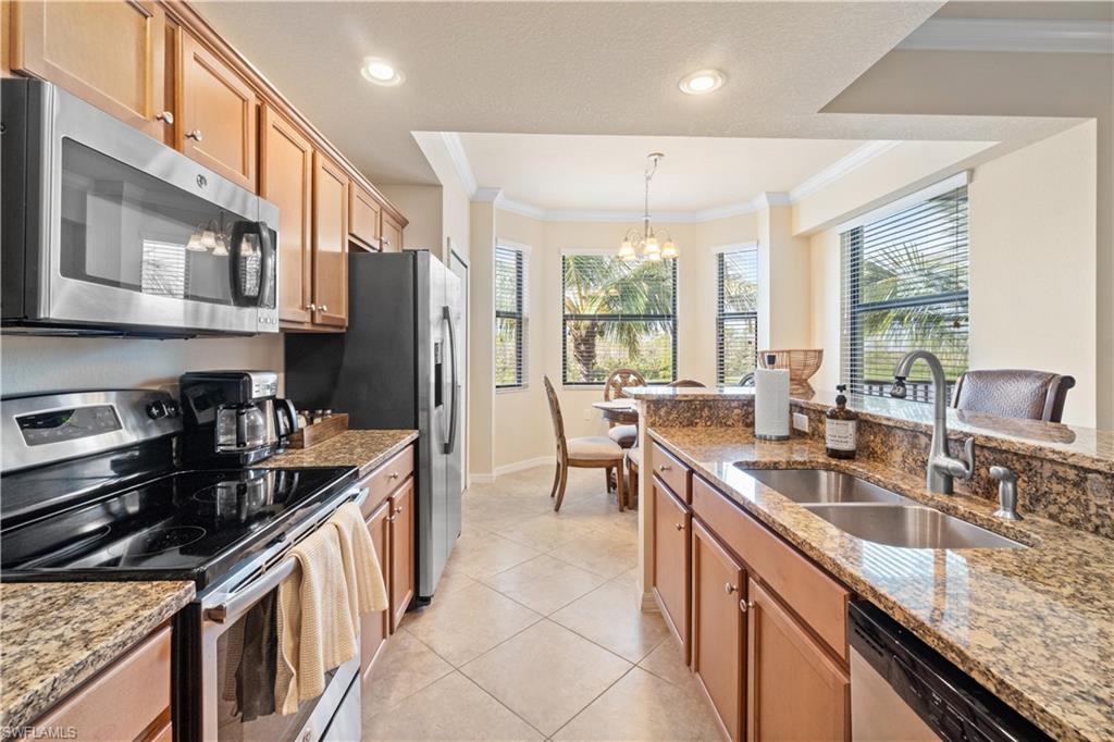 9727 Acqua Court, Unit 436 Naples, FL 34113 - Photo 7 of 40 a kitchen with stainless steel appliances granite countertop a sink stove and cabinets